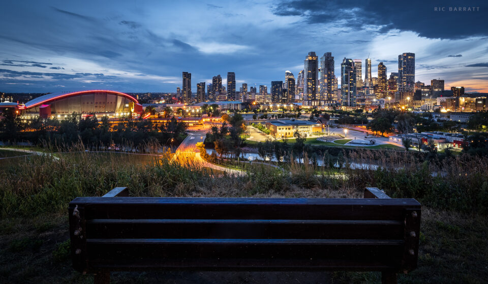 Bench with a view of city centre skyscrapers at night.