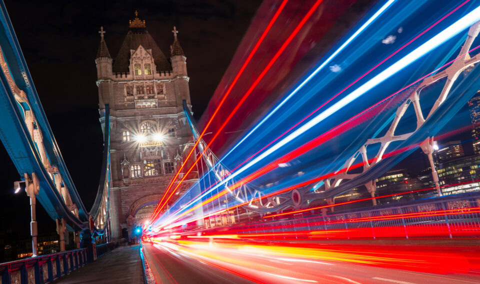 Night view of Tower Bridge with light trails from moving vehicles.