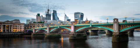 Aqua-coloured bring across a river, will glass skyscrapers in the distance.