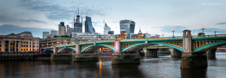 Aqua-coloured bring across a river, will glass skyscrapers in the distance.