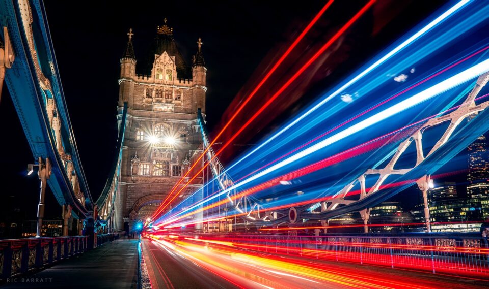 Streaking lights from traffic across London's Tower Bridge at night.