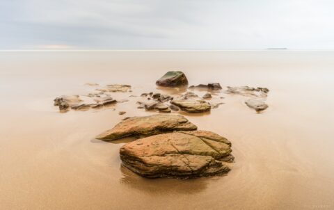 Collection of rocks on a wide empty beach.