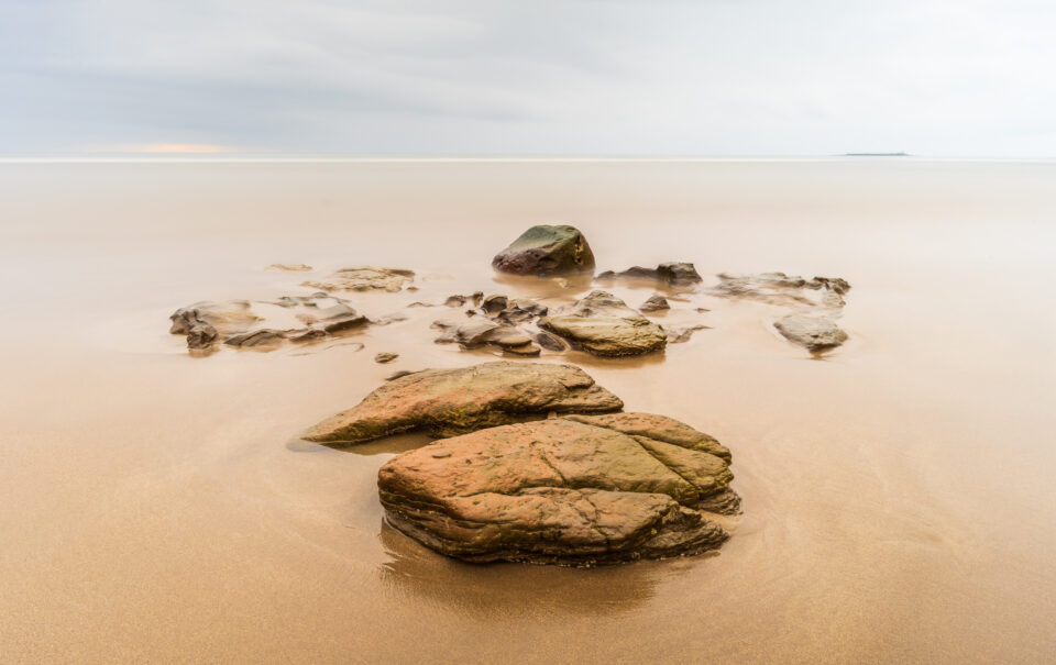 Collection of rocks on a wide empty beach.