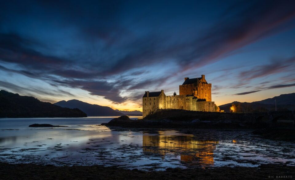 Illuminated lakeside castle at night.