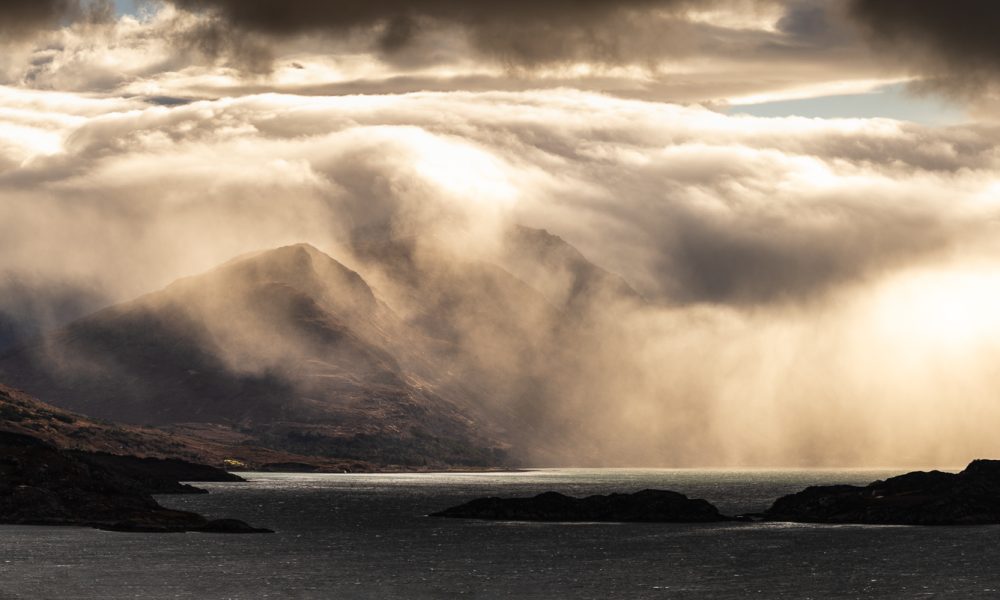 Dramatic storm clouds over lake and mountains.