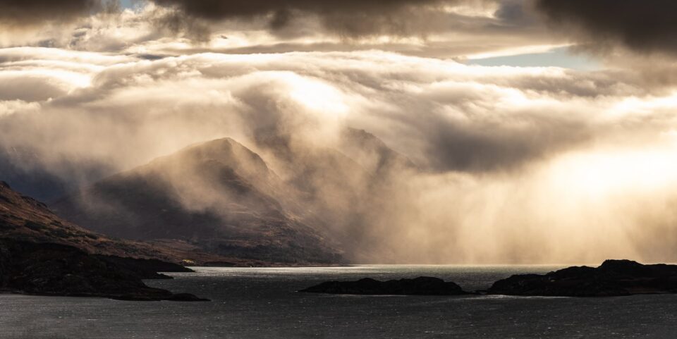 Dramatic storm clouds over lake and mountains.