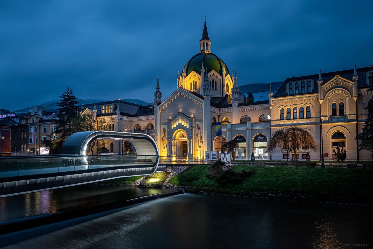 Historic Academy of Fine Arts building in Sarajevo at dusk with illuminated architecture.