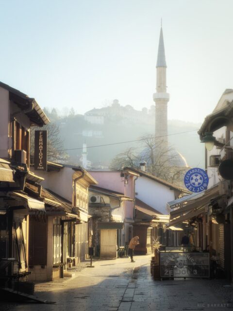 Historic street scene with mosque minaret in background.