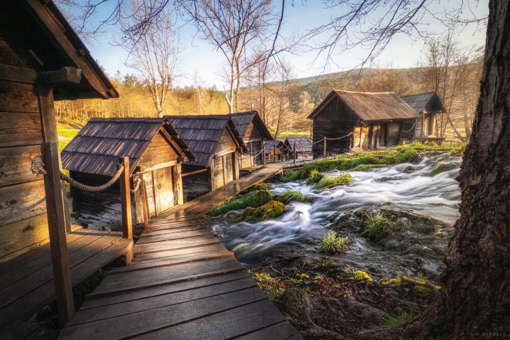 Historic watermills along Mlinići River with flowing water and wooden structures.