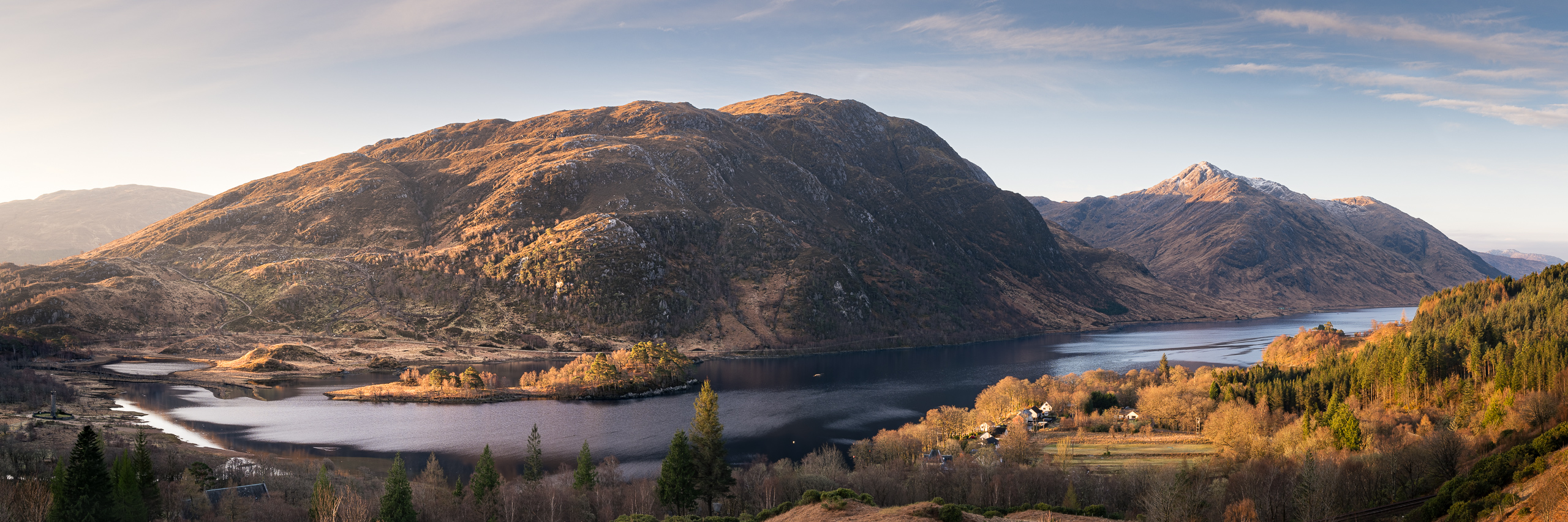 Scenic view of Loch Shiel with surrounding mountains at sunset.