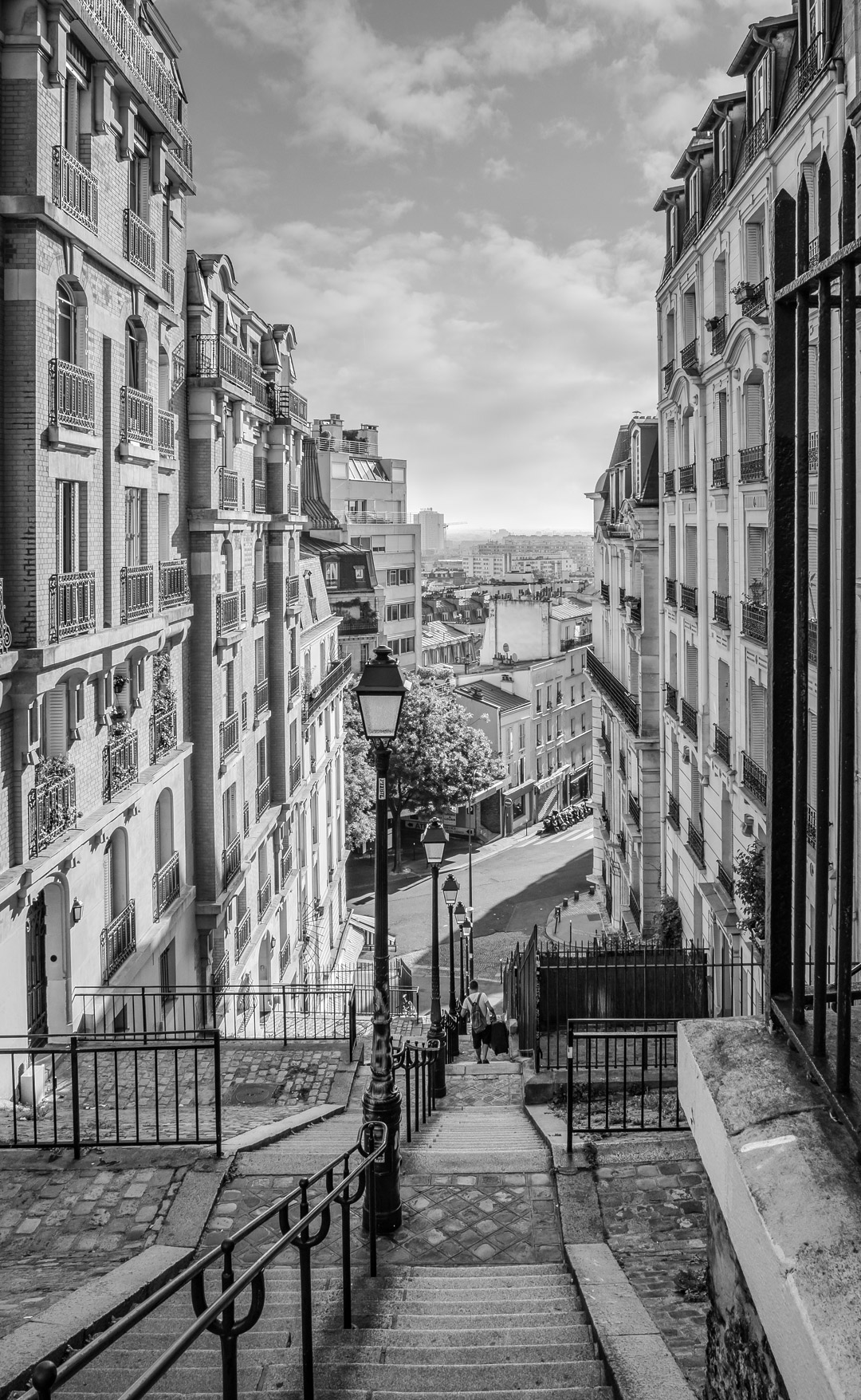 Black and white street scene in Paris with historic buildings and a view of the city skyline.