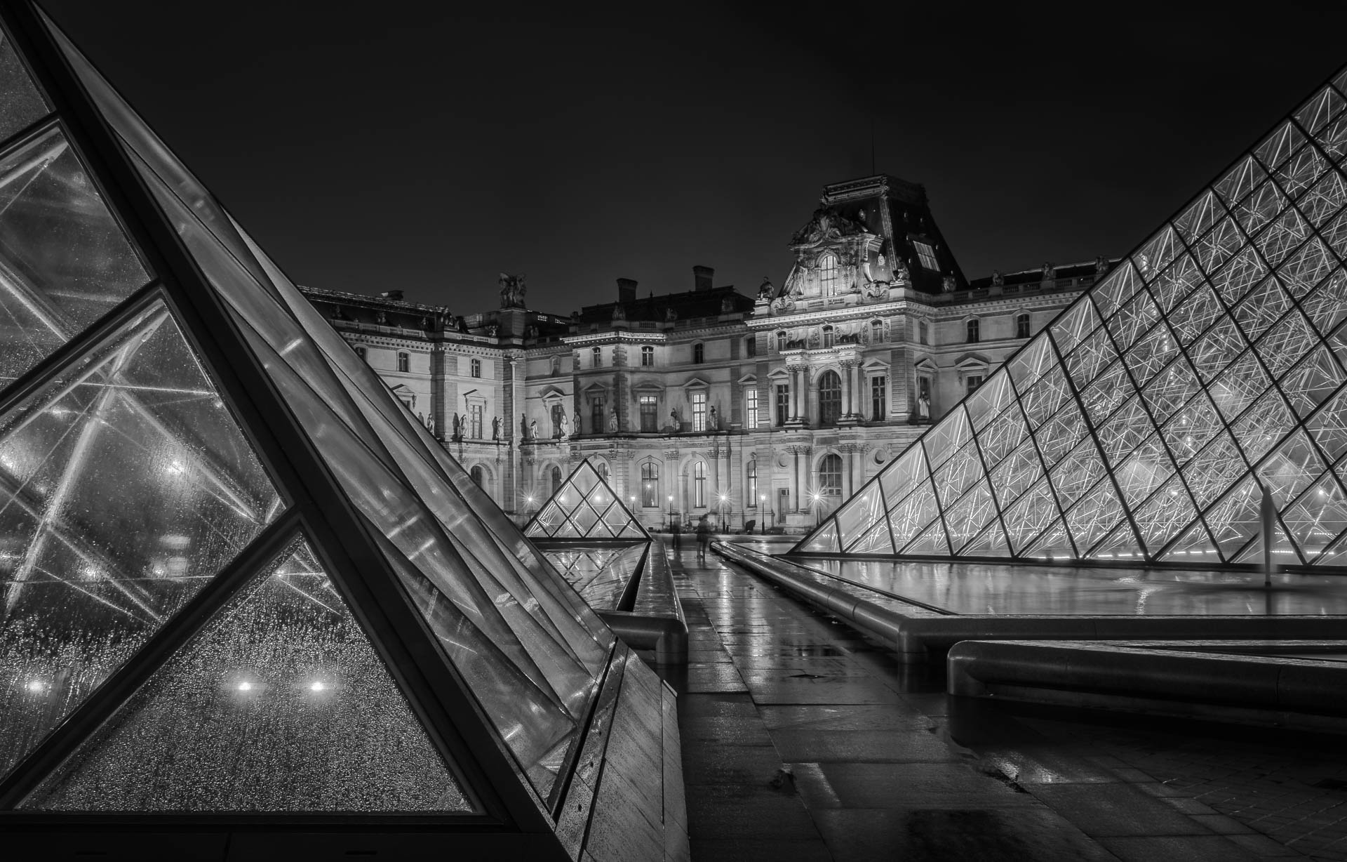 Night view of the Louvre Museum with illuminated glass pyramids in Paris.