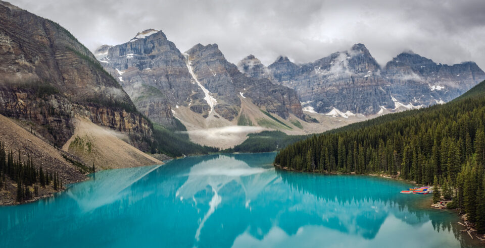 Scenic view of turquoise lake surrounded by mountains and evergreen trees.