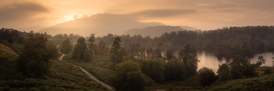 Stormy sky over Tarn Hows with dark clouds and a setting sun.