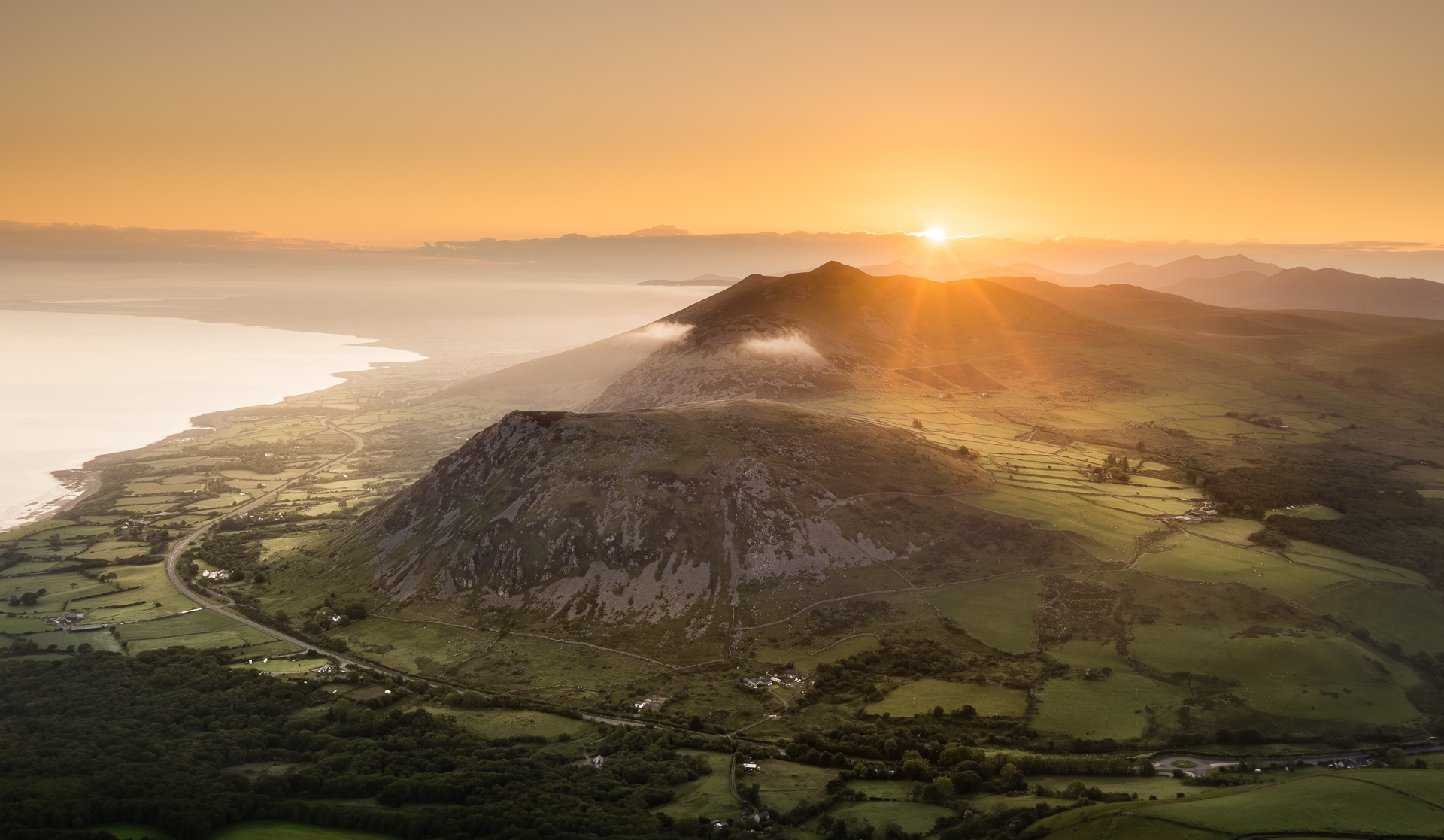 Sunrise over Yr Eifl with scenic landscape and rolling hills in Wales.